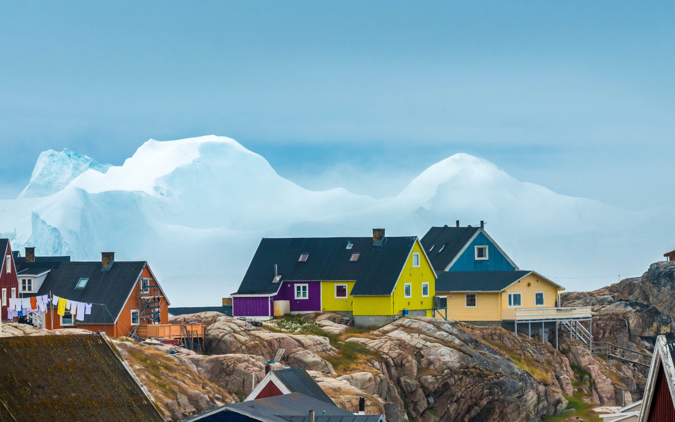 Gr&oslash;nland, Ilulissat, farvede huse og isbjerge i baggrunden