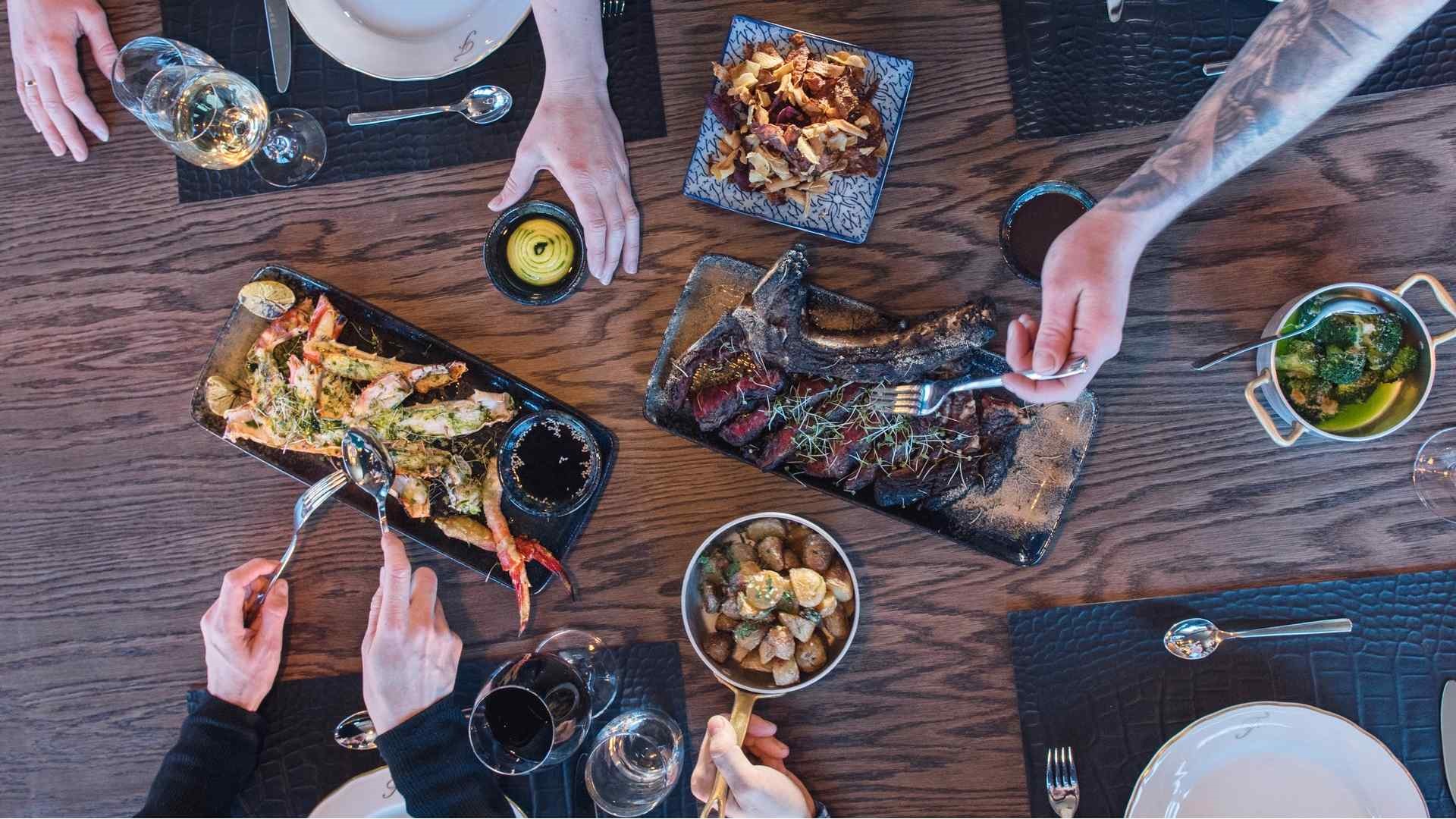 Billed taget oppe fra af fire mennesker der spiser et dejligt måltid